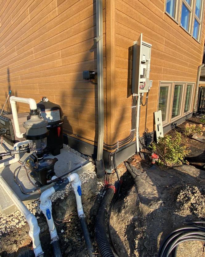 Exterior wall with an equipment panel, liquid-tight conduit and pool pump and filter beside an open trench