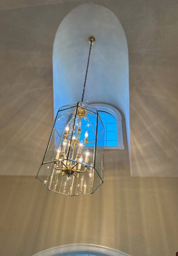 Glass chandelier hanging in a tall arched window alcove