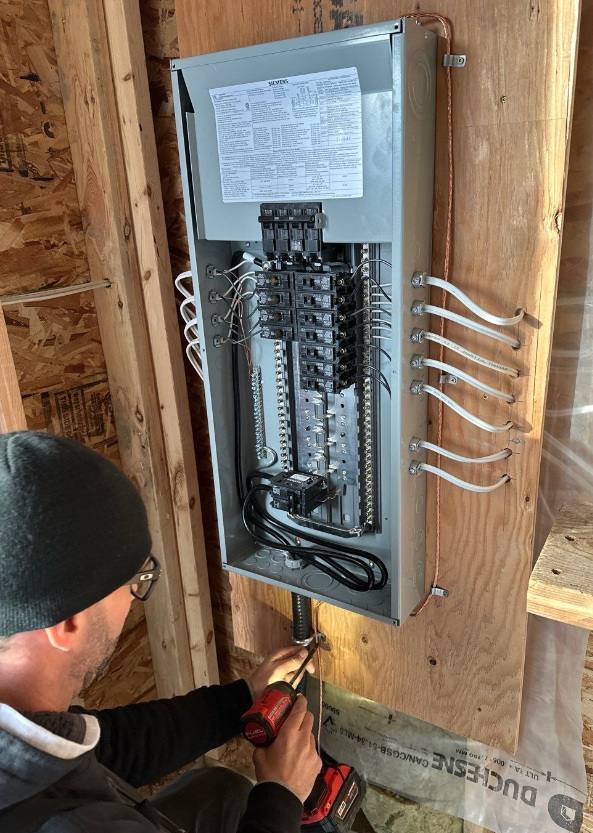 365 Electric electrician terminating circuits in a new breaker panel mounted between wall studs