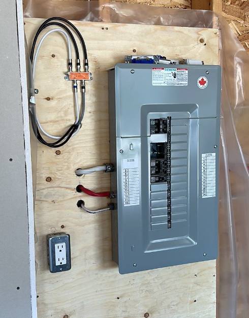 New residential breaker panel mounted on a plywood backboard with labelled circuits